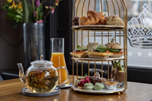 Ein umfangreicher High Tea mit einer Teekanne, einer Flasche Orangensaft und einer Vielzahl von herzhaften und süßen Leckereien.