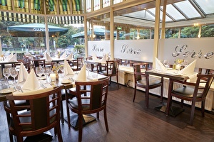 Amrâth Hotel Lapershoek Arenapark Restaurant Vivaldi mit gedeckten Tischen, weißen Servietten und Holzstühlen.