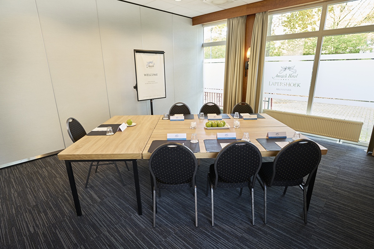 Kleiner Besprechungsraum im Amrâth Hotel Lapershoek Arenapark, quadratische Tischanordnung mit natürlichem Tageslicht und Flipchart.
