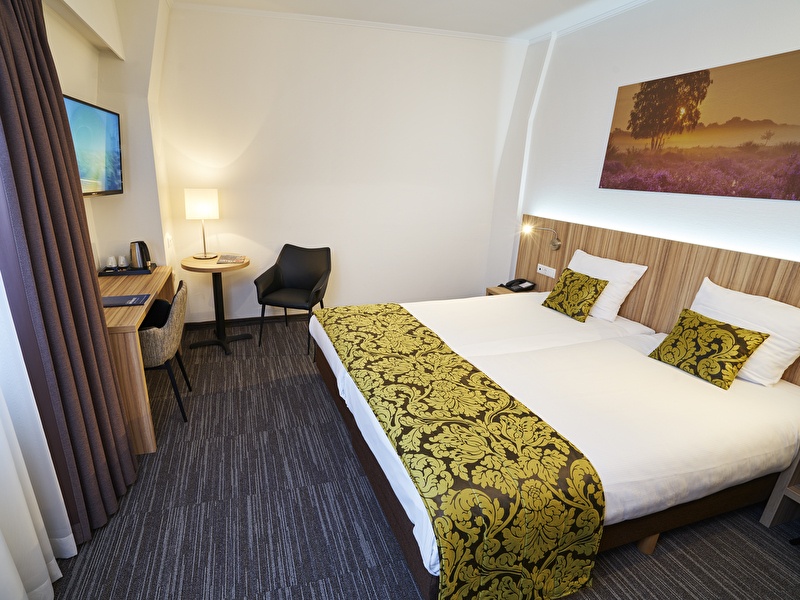 SUperior kamer in Amrâth Hotel Lapershoek Arenapark met een tweepersoonsbed met gele geprinte kussens met hetzelfde sprei