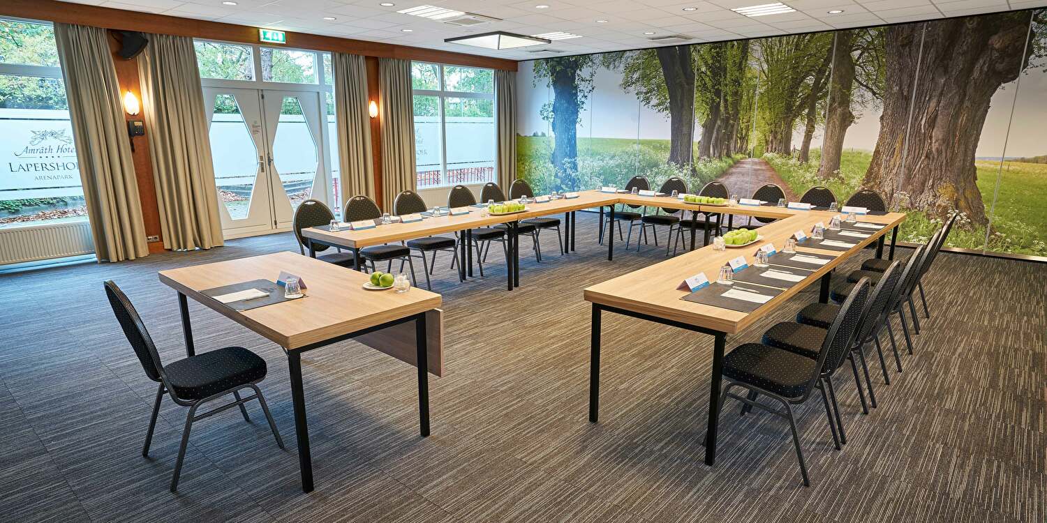 Een vergaderzaal met tafels en stoelen klaar voor een bijeenkomst.